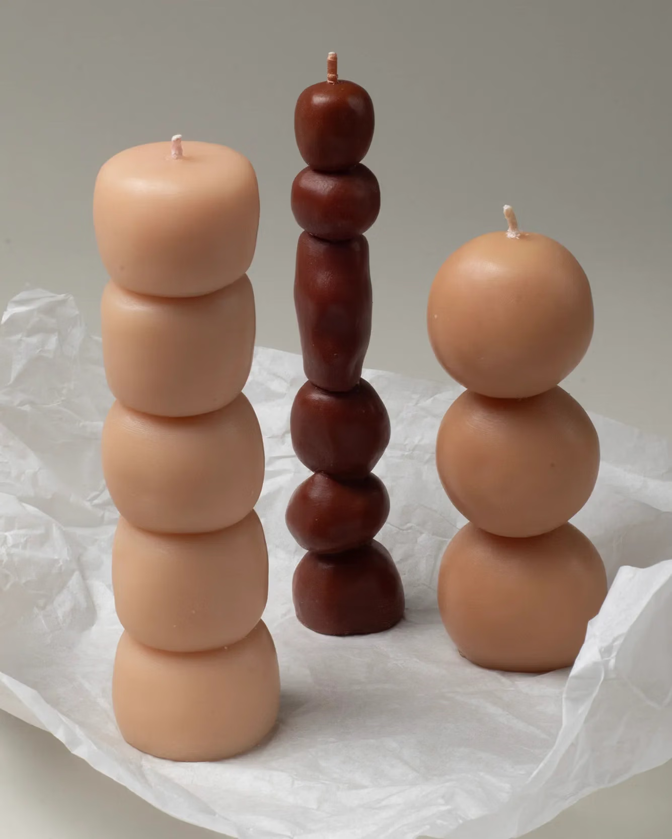 Three candles in off-white, sand and brown color. The candles look like bubbles or stones stacked on top of each other.